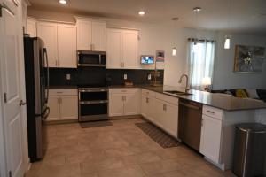 基西米Luxurious 8-Room Oasis near Disney的厨房配有白色橱柜和黑色家电
