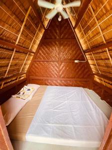 锡基霍尔Destiny Rainbow Beach Resort的稻草小屋内的一张床位,配有吊扇