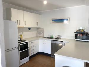 库克敦Endeavour Reach的厨房配有白色橱柜和白色冰箱。