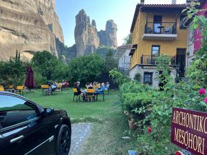 卡兰巴卡Archontiko Mesohori Meteora的停车场停在一间以山为背景的餐厅前