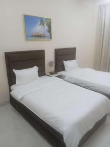 阿吉曼Al Rawda Apartments -Ajman的卧室内的两张床,配有白色床单
