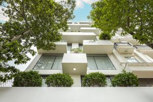 土龙木市LP rental - Minimalist Studio Apartments的白色的建筑,旁边是植物