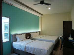 关丹Pantai Regal City Hotel的配有吊扇的酒店客房内的两张床