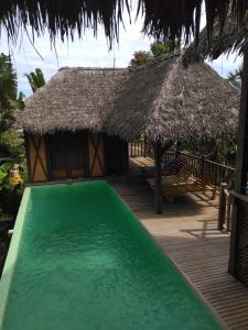 贝岛LOCAVACATION Les Hauts Manguiers Villa 2的一个带游泳池和茅草屋顶的度假胜地