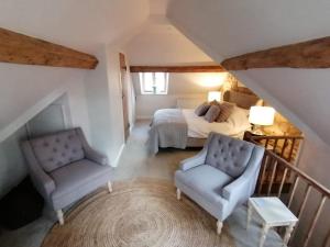 奇平卡姆登Merriman Cottage的一间卧室配有一张床、一把椅子和一张桌子