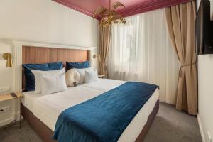 布达佩斯皇庭酒店的一间卧室配有一张带蓝白色枕头的大床