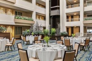 沃尔瑟姆Embassy Suites by Hilton Boston Waltham的宴会厅配有白色的桌椅