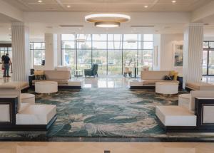 西棕榈滩Hilton Palm Beach PBI的大堂配有沙发、桌子和大窗户。