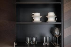 乌日霍罗德ММ GROUP APARTMENT的黑色橱柜,带玻璃杯和餐具及酒杯