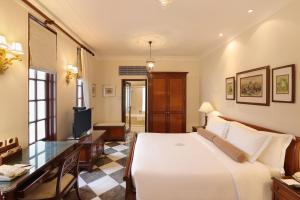 新德里新德里帝国酒店的一间卧室配有一张床、一张书桌和一台电视