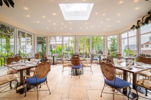 林道施翁花园加尼酒店的用餐室设有桌椅和窗户。