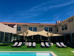 埃斯特雷莫斯Estremoz Hotel的一座建筑前的带椅子和游泳池的酒店