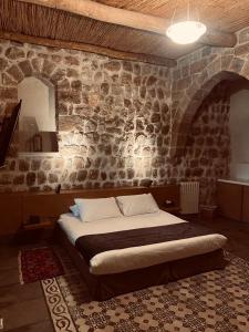 Şaḩrat al QashshDomaine de Chouchene的卧室配有一张石墙内的大床