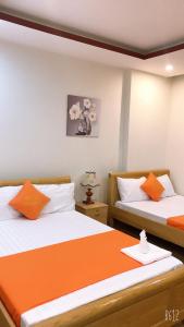 岘港Bao Tran Homestay的橙色和白色的客房内的两张床