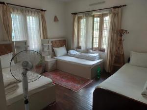 帕坦Nepal christian guest house的小房间设有两张床和风扇