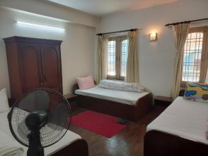 帕坦Nepal christian guest house的客房设有两张床、风扇和窗户。