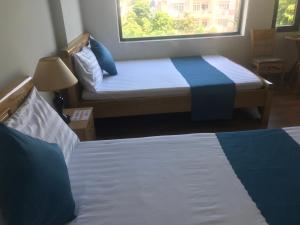 岘港Bao Tran Homestay的配有窗户的酒店客房内的两张床