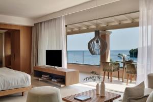 卡拉米San Antonio Corfu Resort (Adults Only)的一间卧室配有一张床,客厅配有电视
