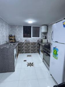 乌姆盖斯Beit Al Hasan بيت الحسن的厨房铺有白色地板,配有冰箱。
