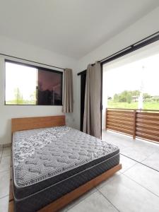 因比图巴Suítes do Vale - Praia do Rosa的一间卧室设有一张床和大窗户