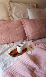 罗兹HOLA Apartamenty Narutowicza的床上的两杯盘子,有粉红色枕头