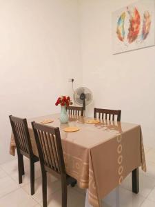 米里Miri Morsjaya HOMESTAY的一张桌子,上面有四把椅子和花瓶