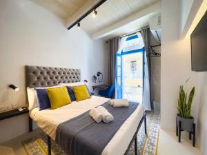 瓦莱塔Mandera's Boutique Suites & Dorms的一间卧室配有一张大床,提供黄色和蓝色的枕头