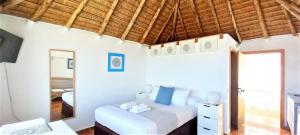 洛斯卡尼奥斯德梅卡Mandala Bungalows - Adults Only的卧室设有白色的床和木制天花板。