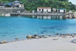Takibe角島シェア&ゲストハウスSumikkoオーシャンビューの犬がいるゲストハウスで特別な交流体験個室とドミトリー的一片岩石海滩和水中的房子