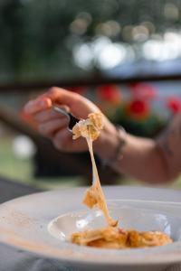 瓦尔佩利内丽维阿穆尔酒店的持有叉子,有食物在盘子上的人