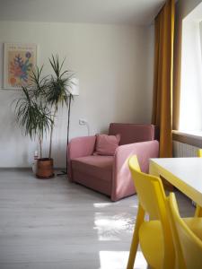 维萨吉纳斯Sunny apartment with lake and forest view的客厅配有粉红色的沙发和植物