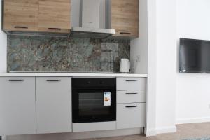 布雷西亚Appartamento Tiffany的厨房配有白色橱柜和黑烤箱。