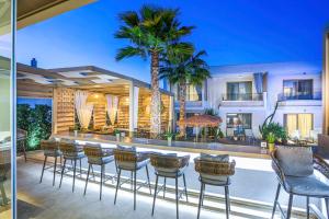 佩科霍里Pefki Deluxe Residences的一个带椅子的庭院和一个带棕榈树的酒吧