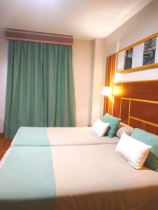 拉卡尔洛塔Hotel Carmen的配有绿窗帘的酒店客房的两张床