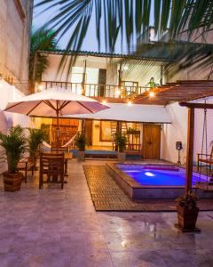 卡塔赫纳HOSTAL LA BOQUILLA的一个带游泳池和遮阳伞的户外庭院