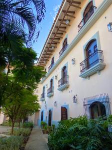 莱昂Hotel La Recolección的一座大型白色建筑,设有阳台和树木