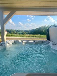 PodiazyOsada Skoczkowo komfortowe domki z jacuzzi nad jeziorem- sauna- balia- prywatny staw wędkarski的后院的按摩浴缸,享有美景