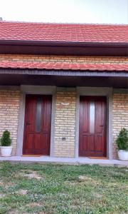 Novi BečejSobe Palasthy的砖楼两扇红门,有草