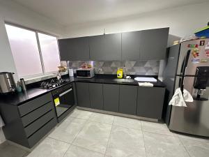 麦德林Gaston2的厨房配有黑色橱柜和不锈钢冰箱