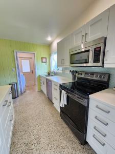 奥兰多GardenHouse @AudubonPark Sleeps 8的厨房配有白色橱柜和黑炉灶烤箱。