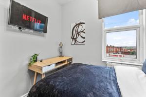 利兹5 Mins From Leeds - 4 Bed - Parking - Sleeps 9的一间卧室设有一张床、一台电视和一个窗口。