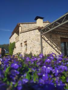 圣格雷戈里奥Can Parés的一座石头建筑,前面有紫色的花朵