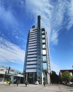 赫尔辛基Flexi Homes Itäkeskus的前面有车的一座高大的玻璃建筑