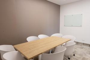 巴兰基亚Distrito 90的一间会议室,配有木桌和白色椅子