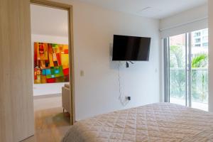 巴兰基亚Habitech soho 55-2的卧室配有一张床和壁挂式平面电视。