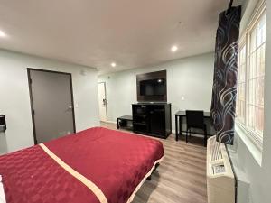 安大略Express Inn & Suites Ontario Airport的一间卧室配有红色的床和电视