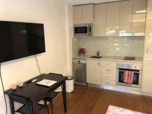 悉尼Lovely refurbished 1 bed near marina + parking的一间带桌子和电视的小厨房
