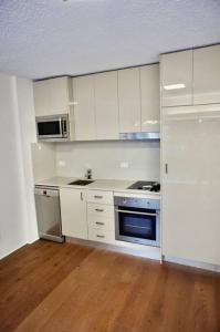 悉尼Lovely refurbished 1 bed near marina + parking的厨房配有白色橱柜和炉灶烤箱。