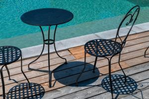 Gaillac-ToulzaChaumarty Ecogîtes©的游泳池畔的一张桌子和四把椅子