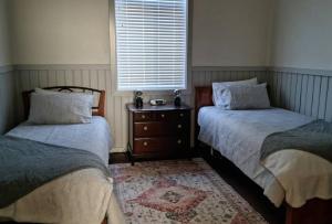 彭伯顿Millhouse on Pine的一间卧室设有两张床、一个梳妆台和窗户。